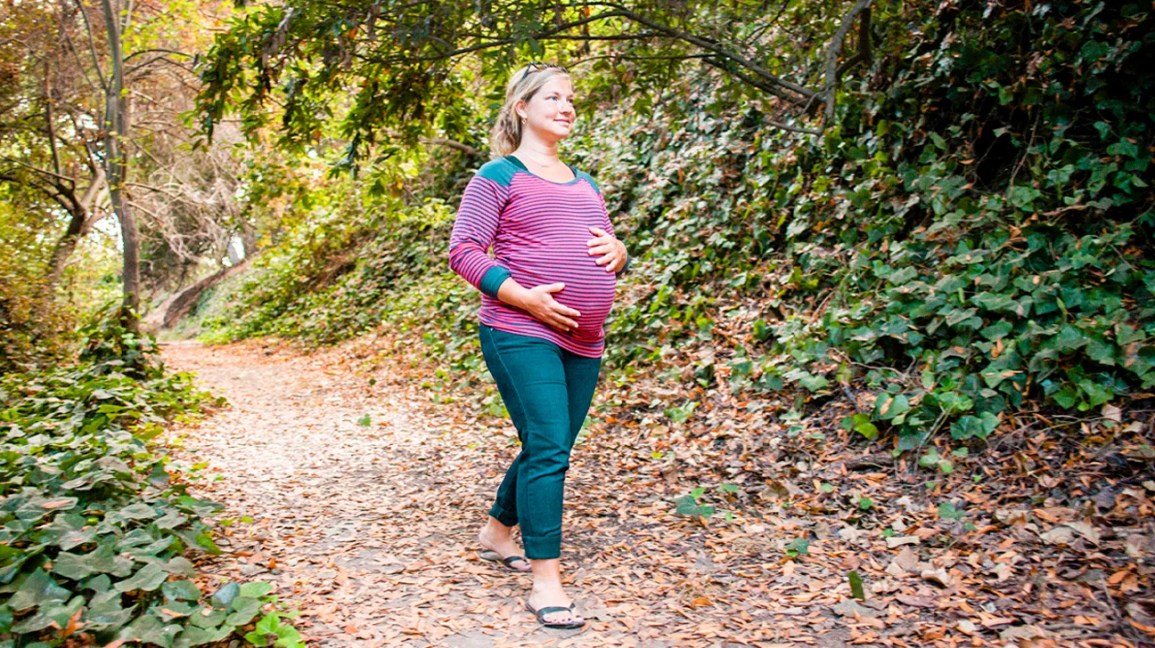 A pregnant person in a forest.