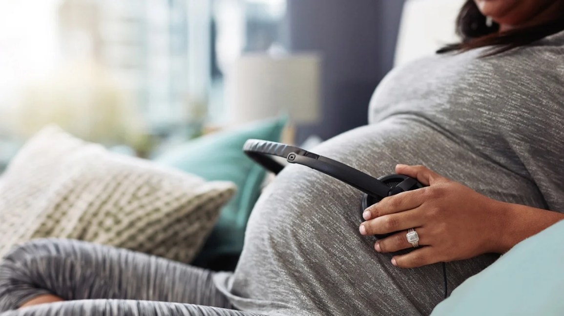 Pregnant person with headphones on belly